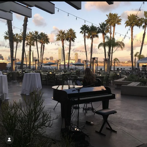 A Music SD pianist performing on a palm-lined San Diego terrace at sunset