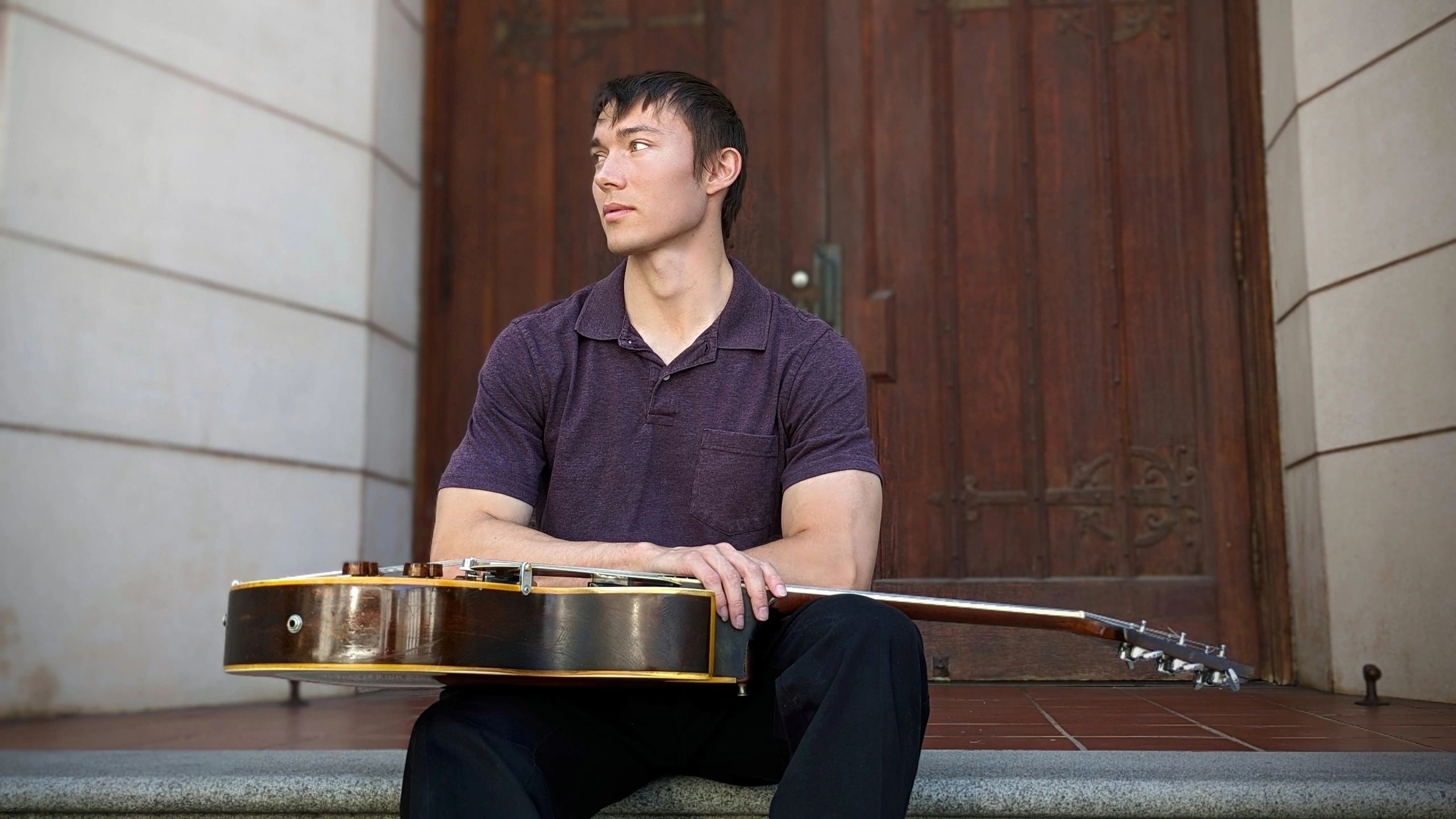 Alex Ciavarelli seated with his archtop jazz guitar