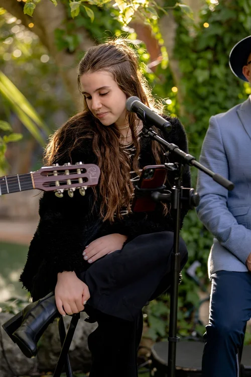 Lauren Raftery seated beside a microphone during an outdoor performance