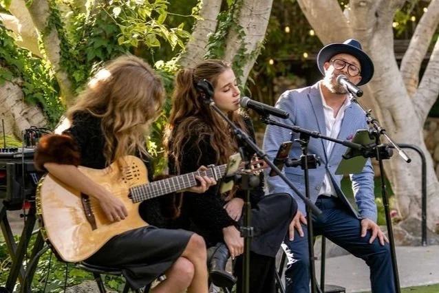 Acoustic guitar, vocals and piano trio performing for guests