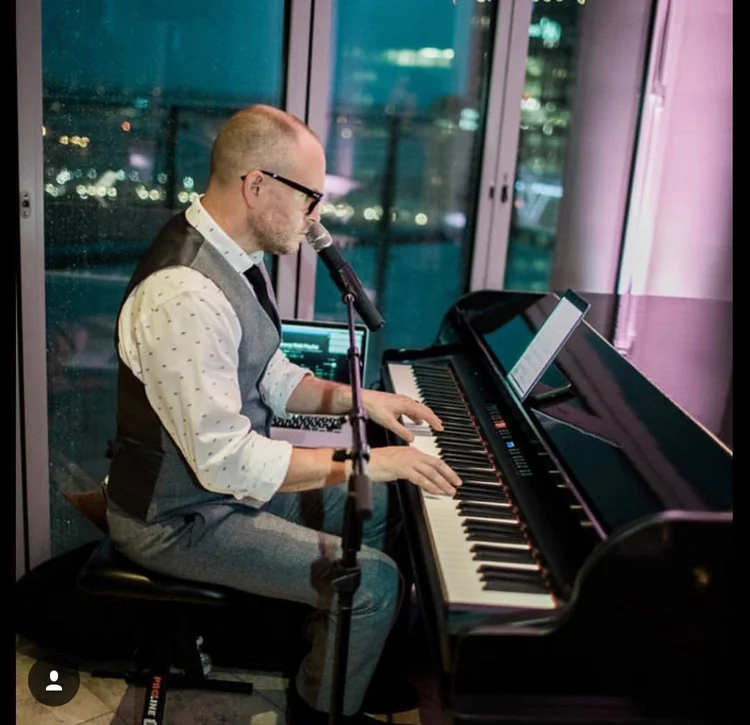 Eric singing and playing piano at an evening venue performance